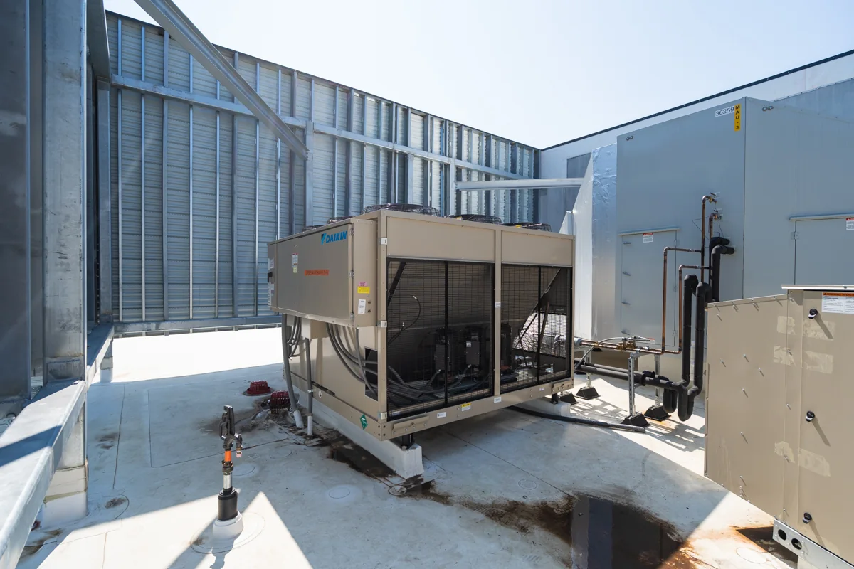 Air-cooled HVAC equipment and refrigerant piping on the roof.