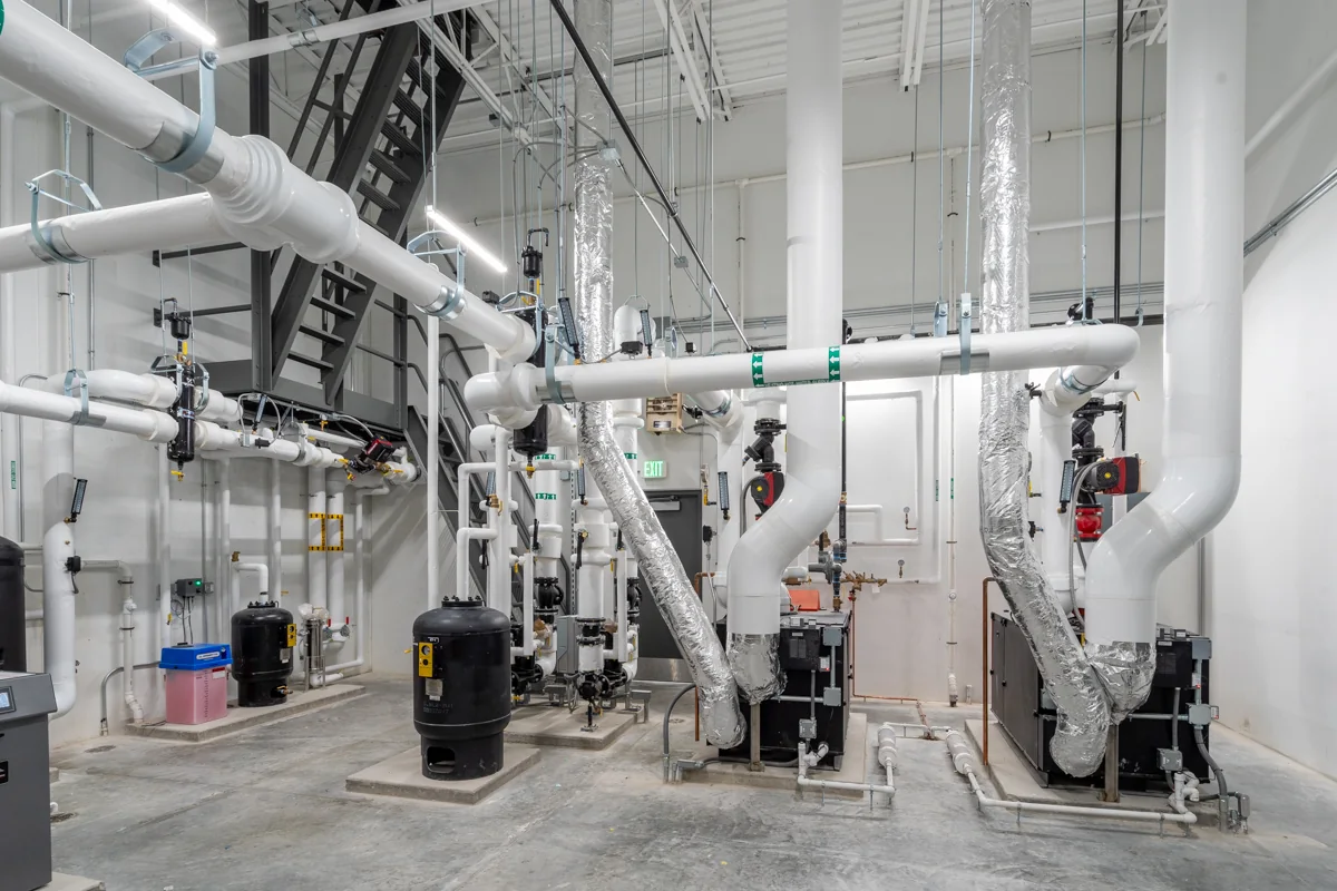 Housby Mack mechanical room with boilers, pumps, piping, and controls.
