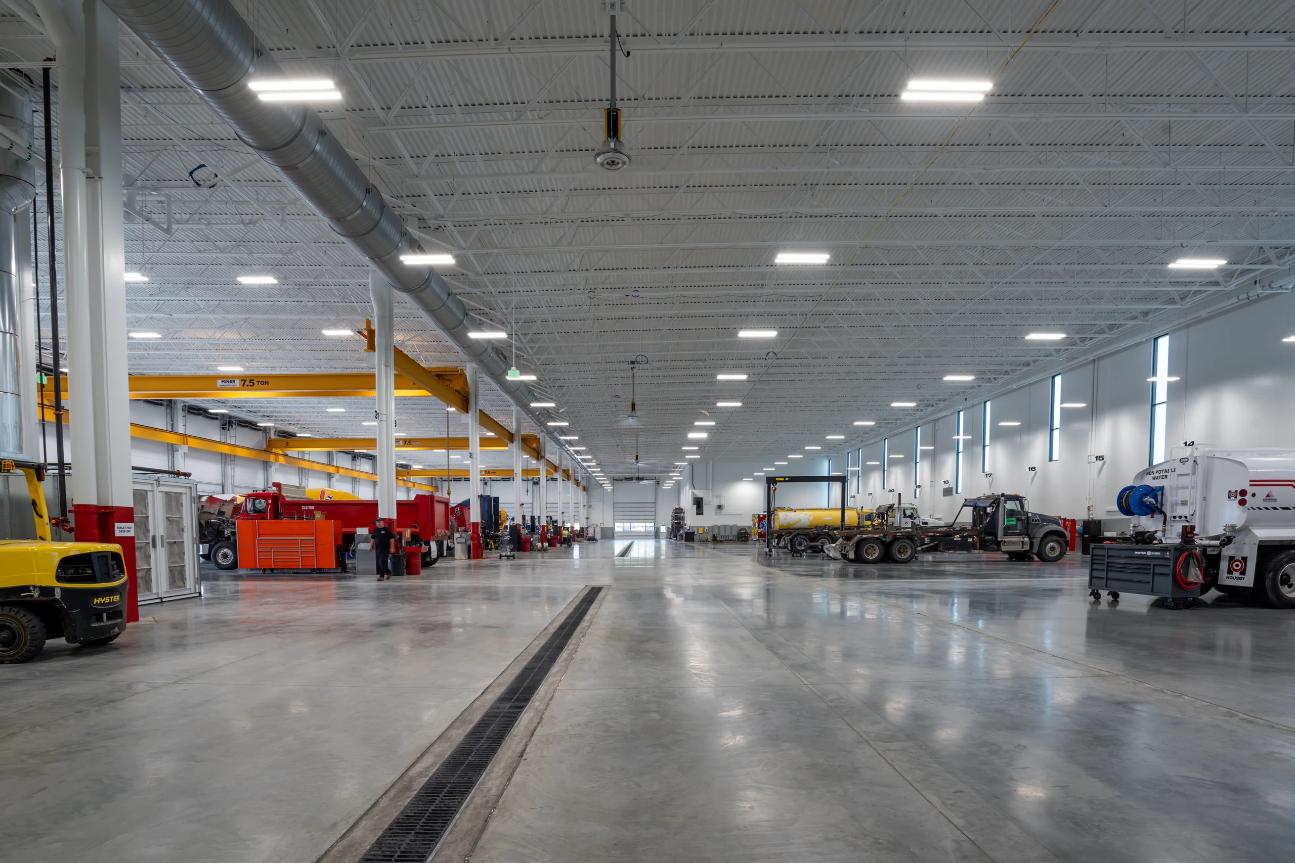 Housby Mack service floor with heavy equipment, overhead cranes, ventilation, and industrial lighting.